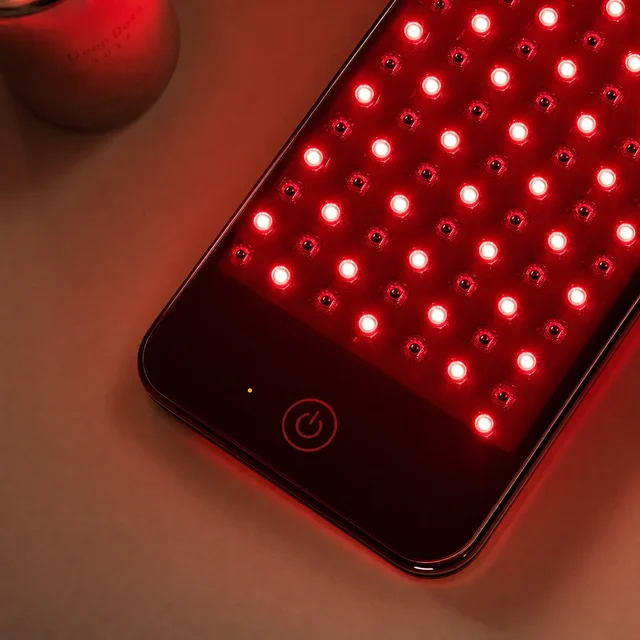 Macro close-up of the Deep Dose Solo LED panel glowing red beside the engraved device casing
