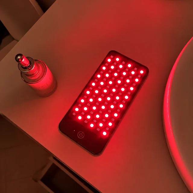 Deep Dose Solo glowing red on a bathroom vanity next to a serum bottle